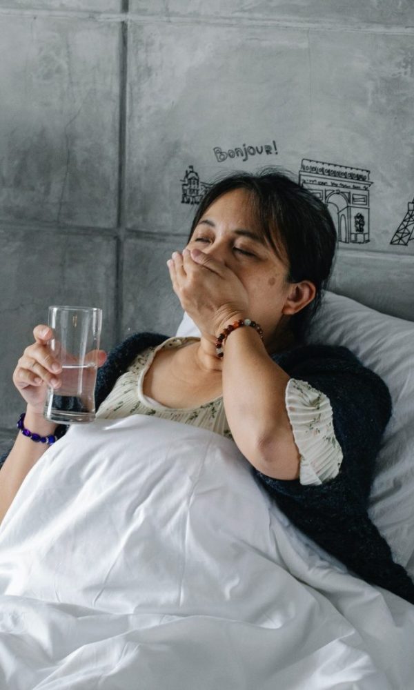 A woman taking pills while resting in bed