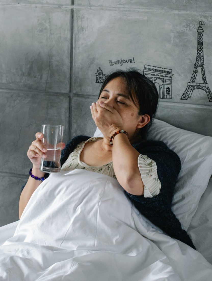 A woman taking pills while resting in bed