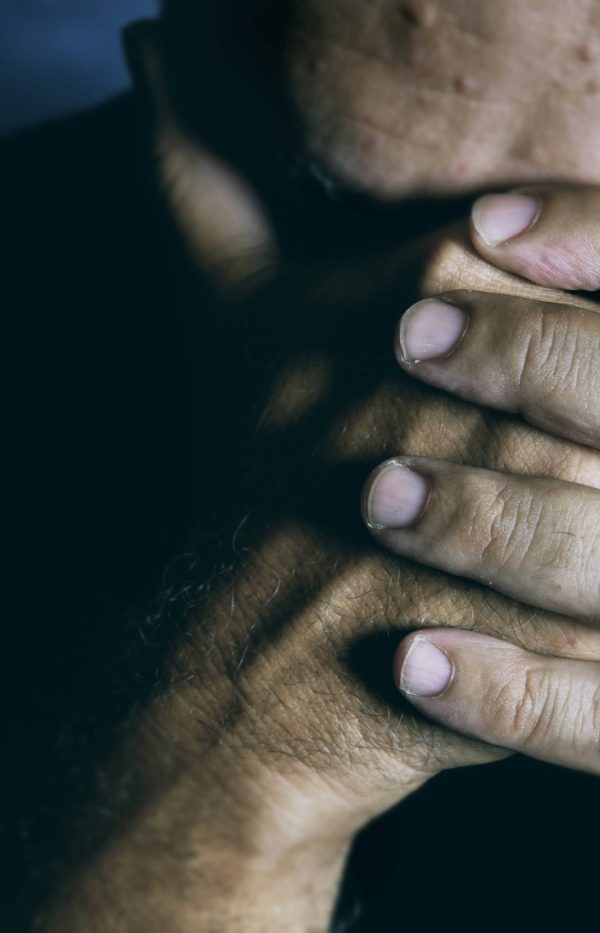 An older man covering his face with his hands